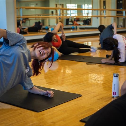 Students engaged in group exercise doing side planks on mats.