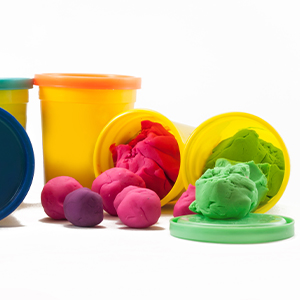 Several Play-Doh containers. Two of them are on their side, with the caps off and Play-Doh spilling out.