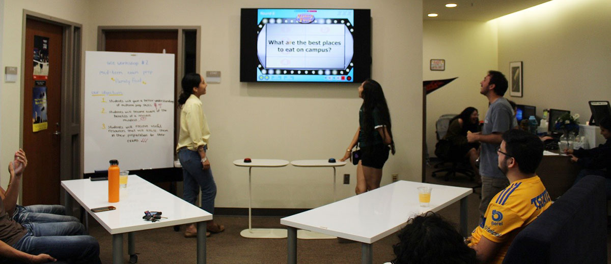 Group of students playing a game and looking at a TV